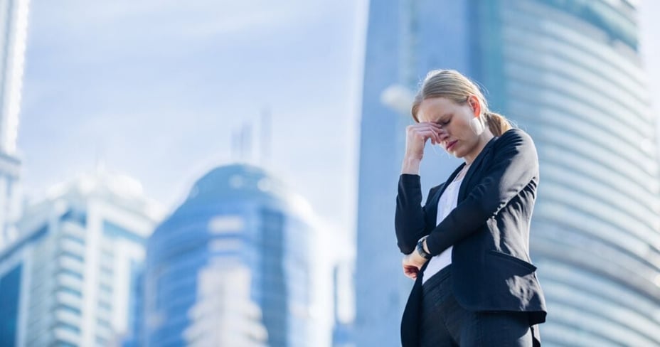 Mujer en la ciudad en día soleado tomándose la cabeza por problemas del mercado inmobiliario