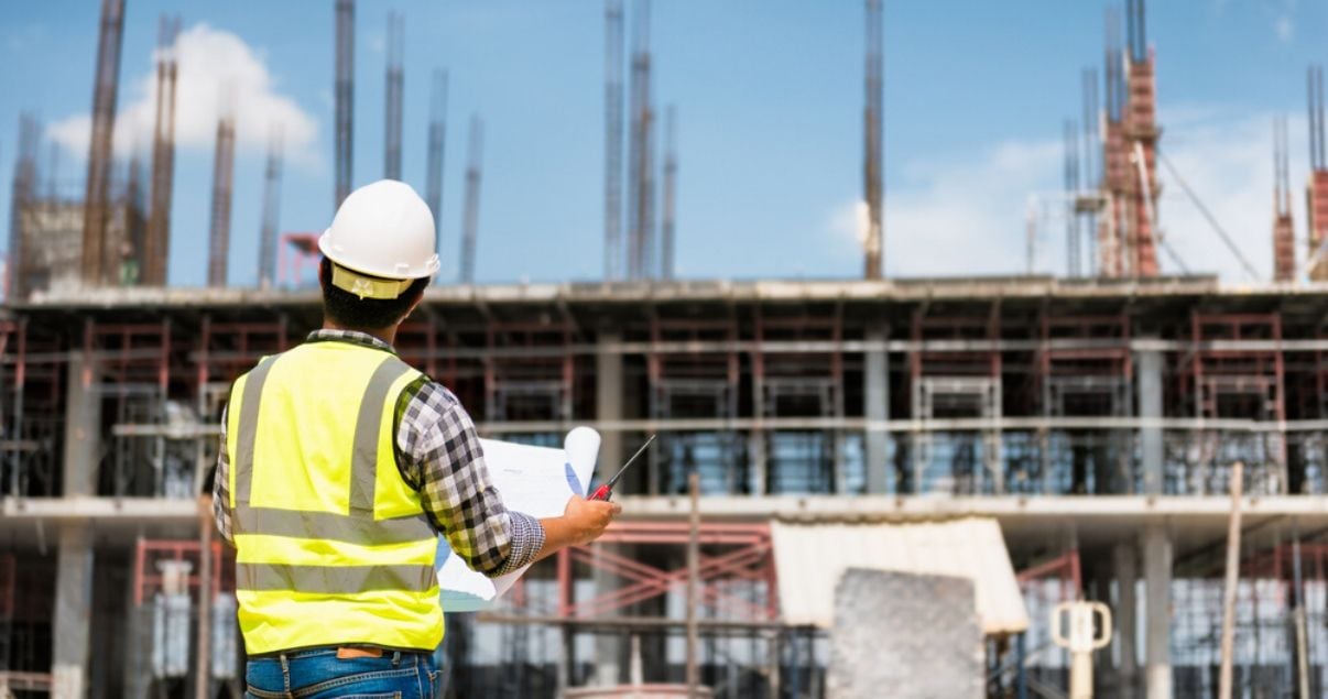 Ingeniero sosteniendo planos del proyecto de apartamento en pozo observando el avance de obra