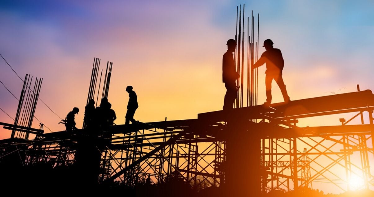 Obreros en atardecer soleado construyendo apartamentos en pozo