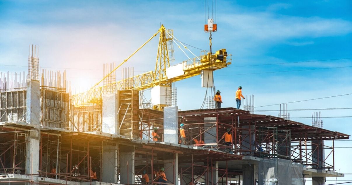 Obreros en un día soleado construyendo un edificio para vender apartamentos en pozo
